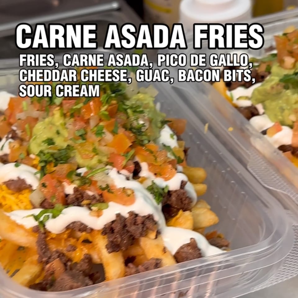 Carne Asada Fries with pico de gallo, guacamole, cheese, and sour cream in a plastic container.